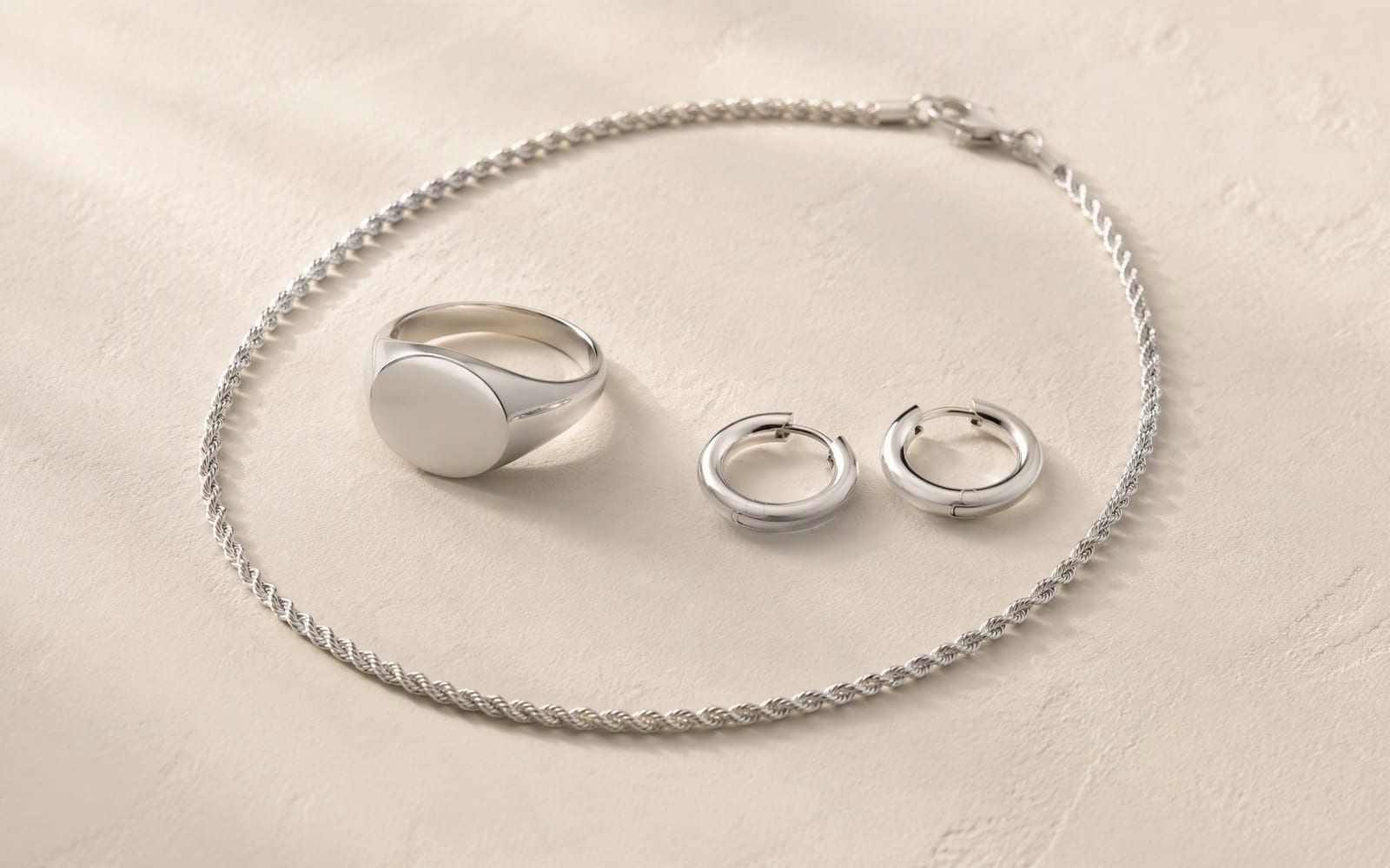 925 sterling silver ring, chain and hoop earrings on a linen surface